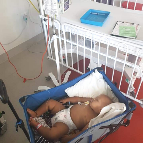 CJ lies in a hospital crib receiving cancer treatment.