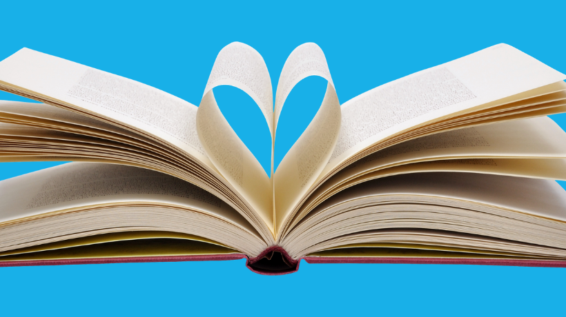 A book lies open flat with pages equally distributed each side - in the very centre, two pages have been curled toward each other to form a heart-shape; the background is light blue.