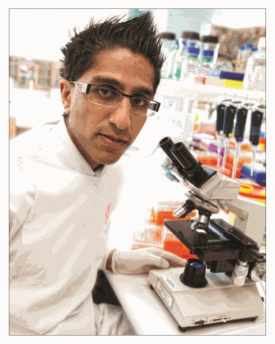 Doctor Rishi Kotecha in a lab with a microscope