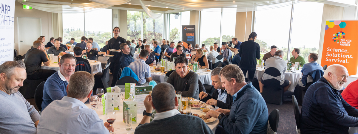 Golfers are seated at many round tables in the club house preparing for lunch and speeches.