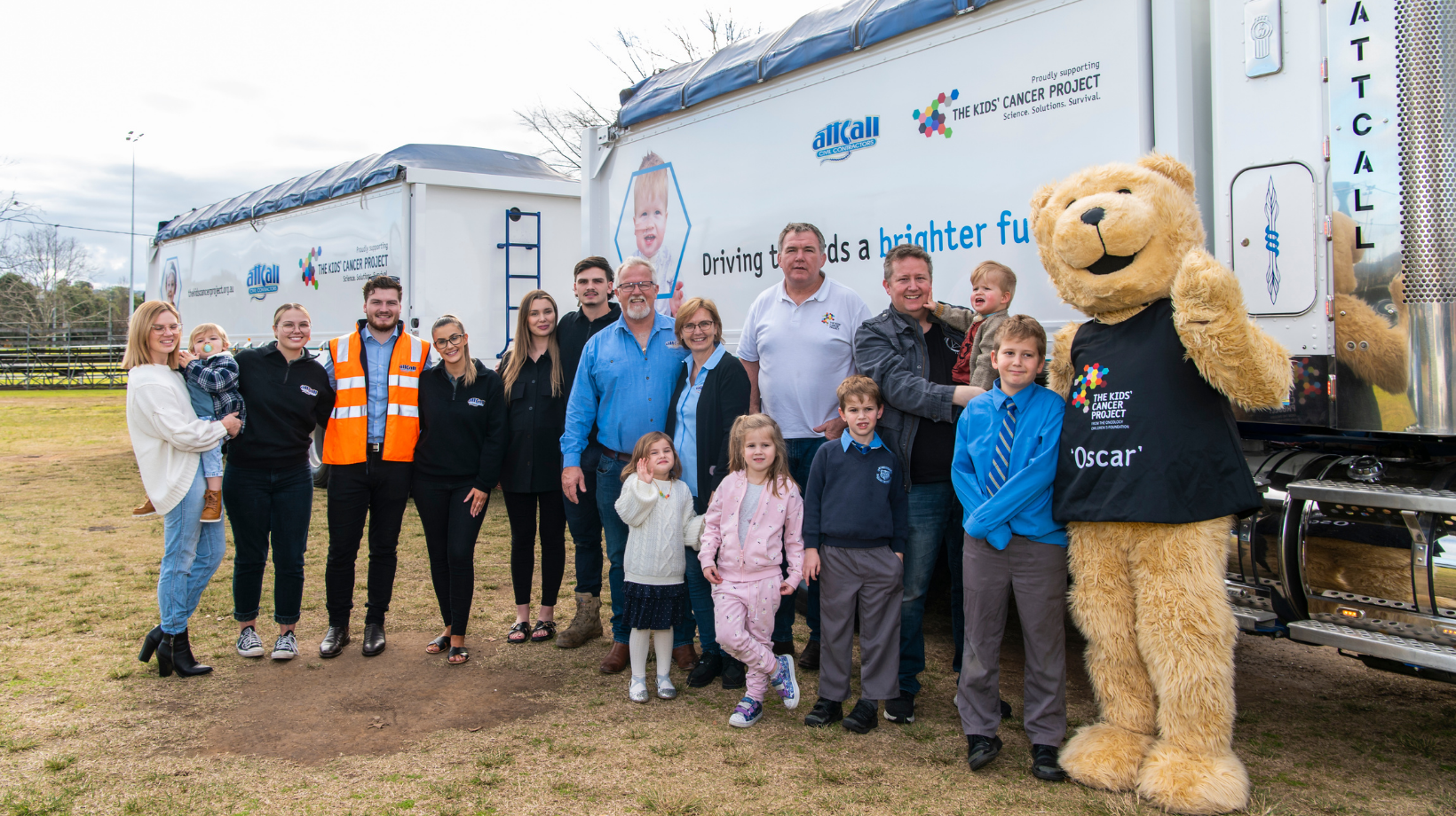 The Attcall team stand with TKCP CEO Owen Finegan in front of a large, 2-trailer truck that has TKCP messaging on the side to raise awareness for kids' cancer.