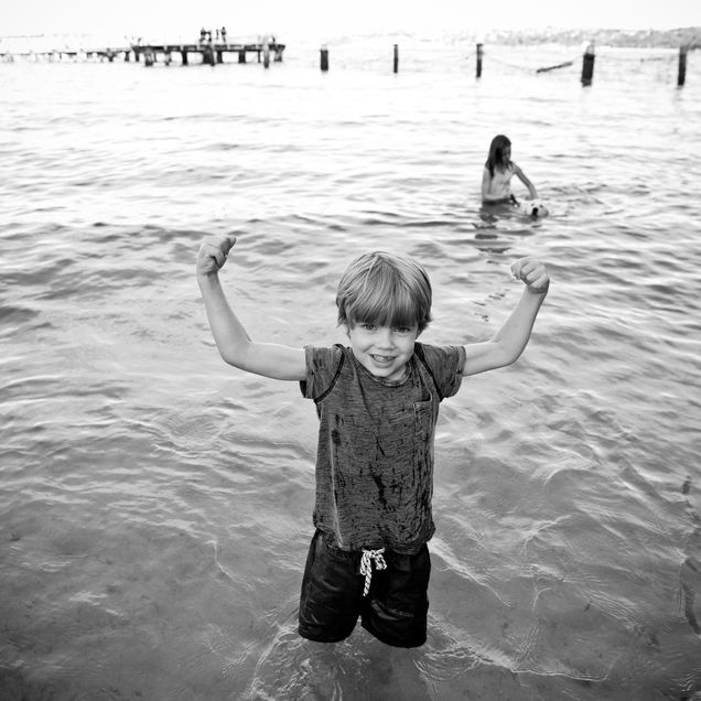 Black and white photo of Murray playing in the ocean, striking a pose showing off his arm muscles