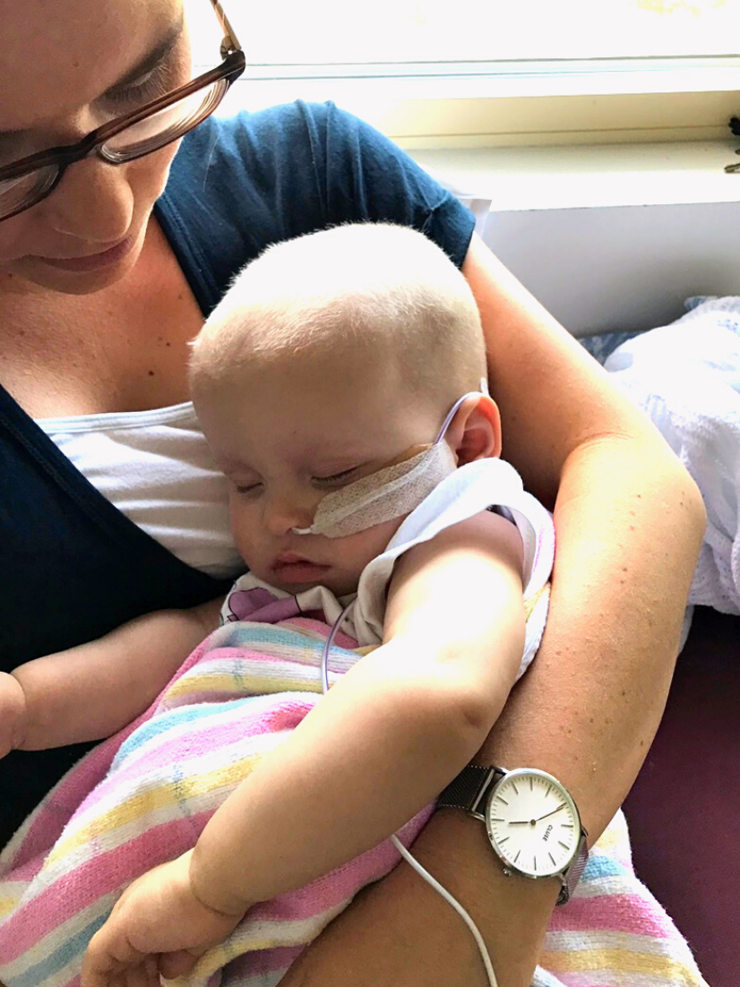 A young Adelaide, resting whilst wrapped in a blanket being held by her mum, Laura