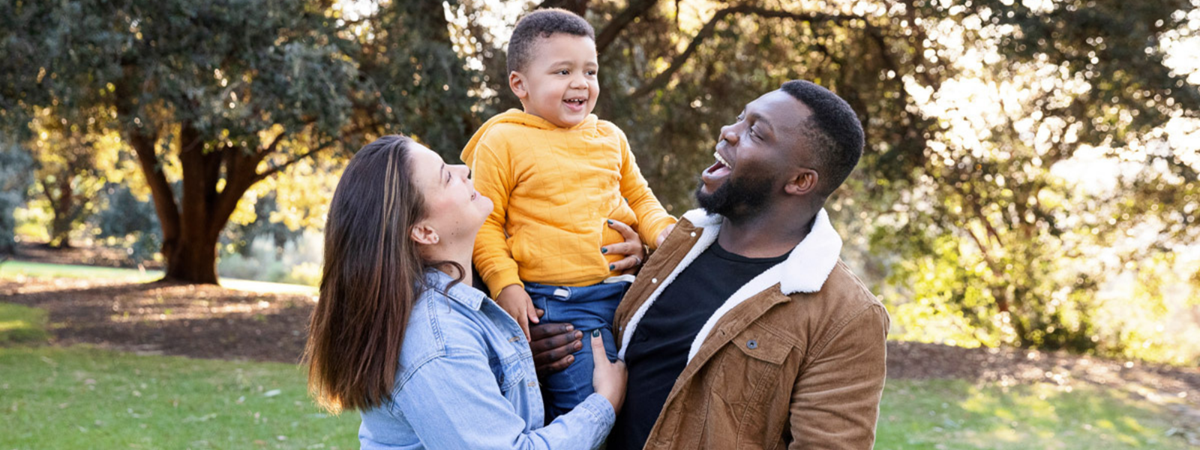 CJ, Mum and Dad share a group hug in a beautiful park.