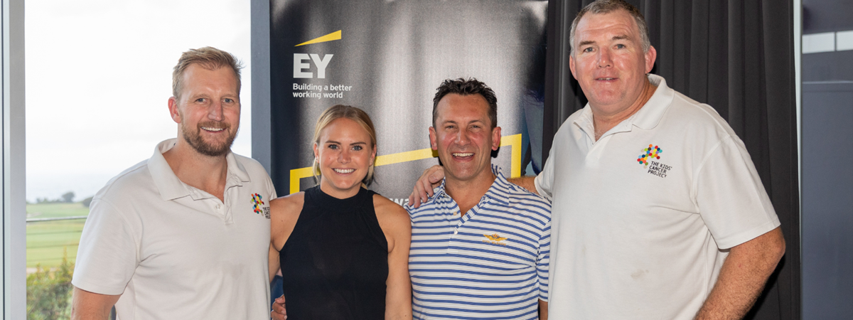 Owen Finegan and 3 golfers smile for a photo in front of a banner with the branding: "EY Building a better working world"