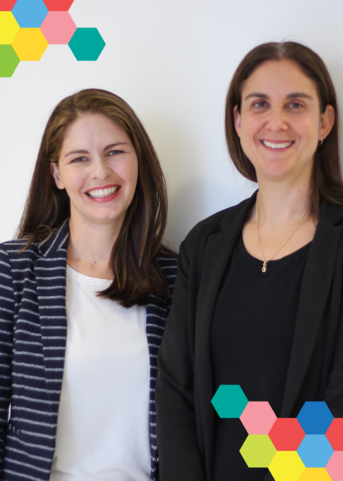 Dr Jennifer Cohen and Professor Claire Wakefield smile in front of a white backdrop; colourful hexagon clusters frame the picture on opposing corners.