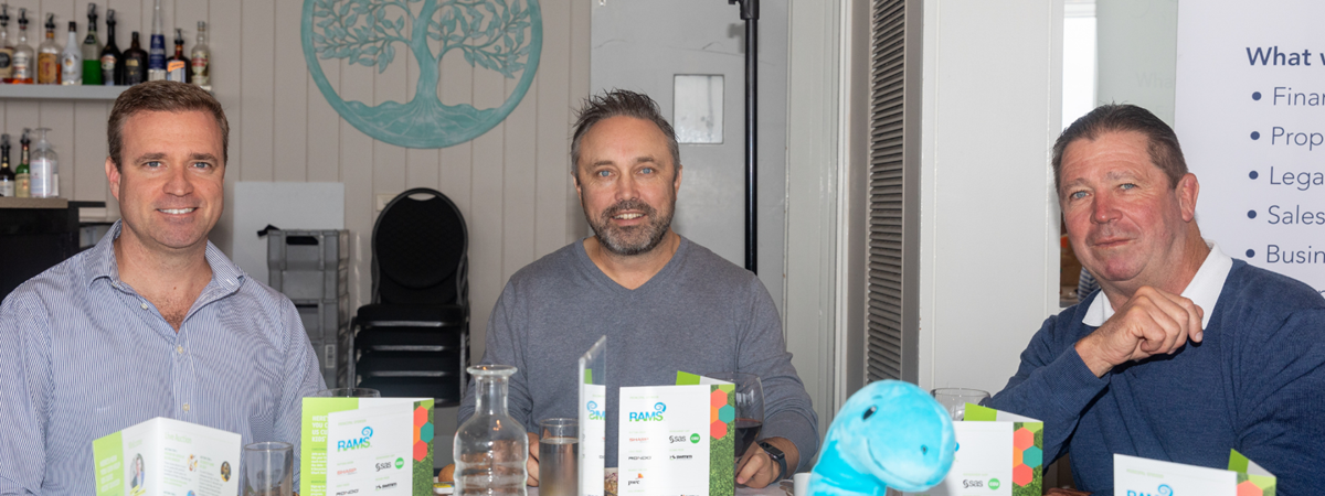 3 golfers seated at one table smile for the camera as they enjoy the festivities of the day.