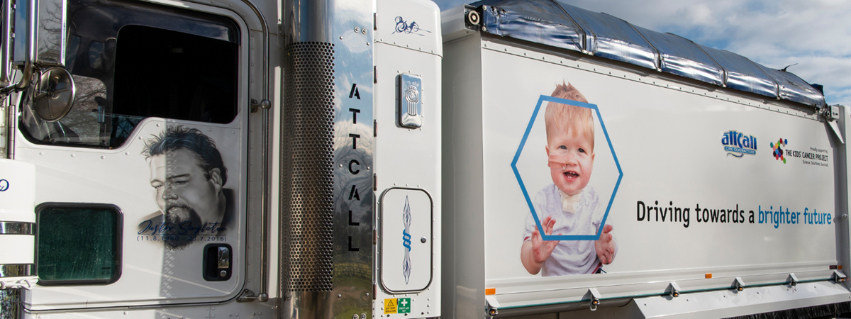 A close-up image of the collaboration truck - the 1st trailer features a picture of Eli during treatment and branding for Attcall and TKCP; the door of the cab features a drawing of Justin Singleton to honour his memory.