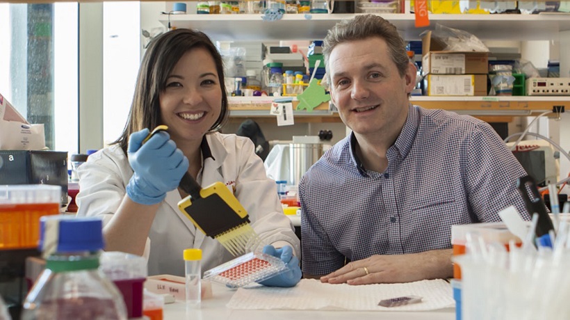 A man who has donated funds in a lab with a woman performing scientific research for kids with cancer