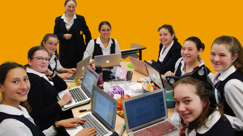 A group of students gather around desks covered in laptops, snacks and other supplies in preparation for their participation in the challenge.