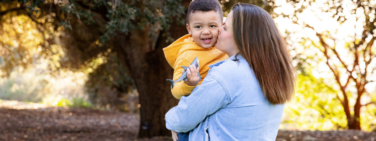 CJ gets kisses from Mum in the park while playing with his little toy shark.