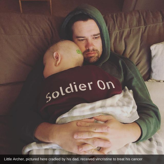 A small boy, Archer, hugs his Dad while they sit on the couch; Archer's back is facing the camera which shows the words 