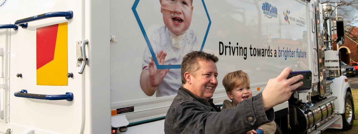 Eli Northey, one of the cancer fighters featured on the Attcall truck poses for a selfie with his Dad, Pete in front of the truck with his picture on it.