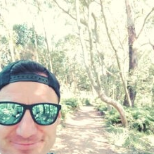 Lloyd Evans takes a smiley selfie while hiking a bush track.